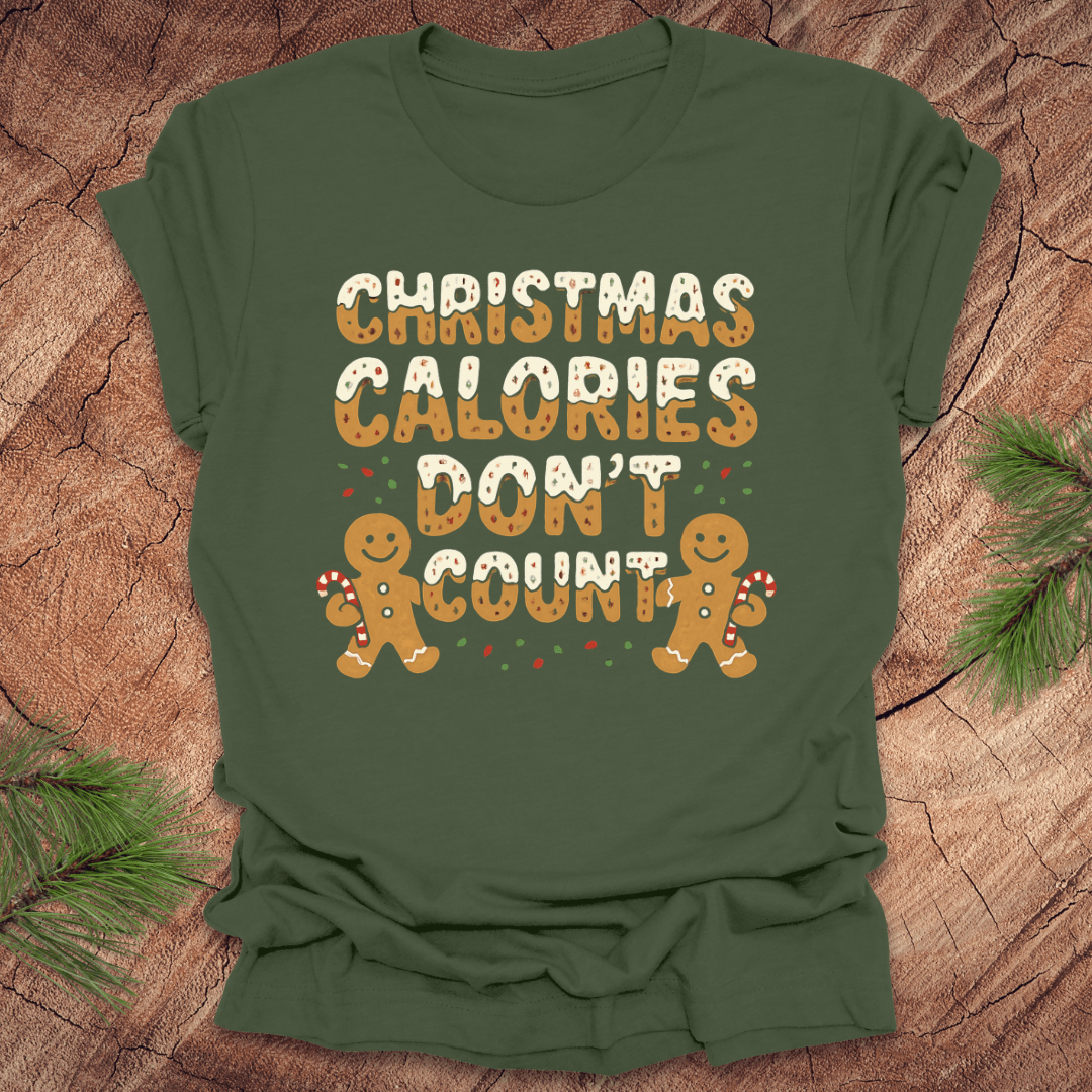 Green tshirt with festive gingerbread text, 'Christmas calories don't count' with gingerbread men on a wooden background.