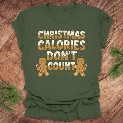 Green tshirt with festive gingerbread text, 'Christmas calories don't count' with gingerbread men on a wooden background.