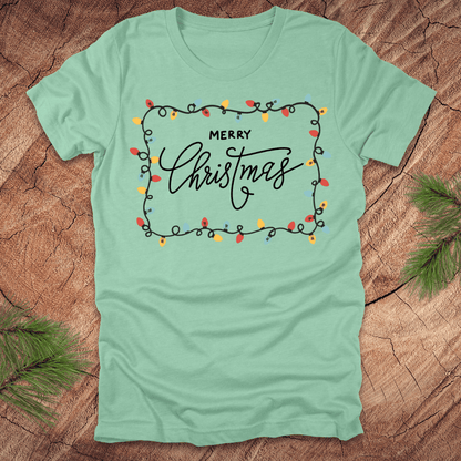 Mint Green t-shirt with christmas lights graphic and 'Merry Christmas' design on a wooden surface