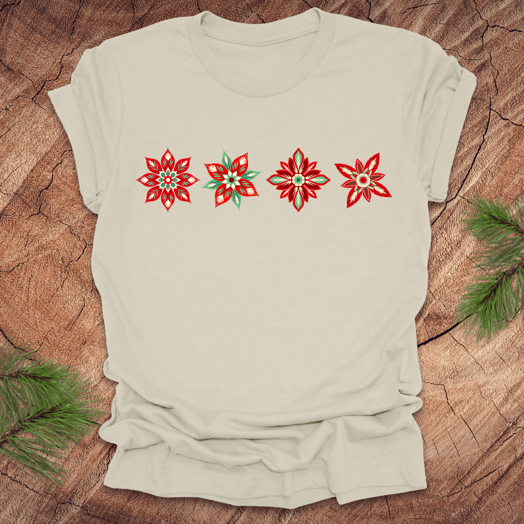 Beige t-shirt with red and white poinsettia flower designs on a wooden surface