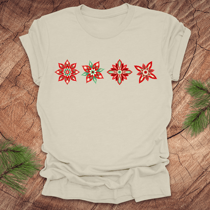 Beige t-shirt with red and white poinsettia flower designs on a wooden surface