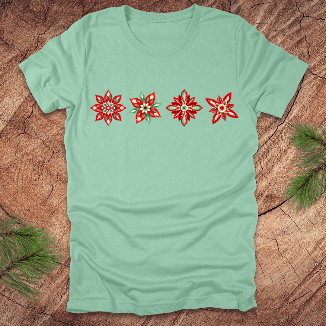 Light green t-shirt with red and white poinsettia flower designs on a wooden surface