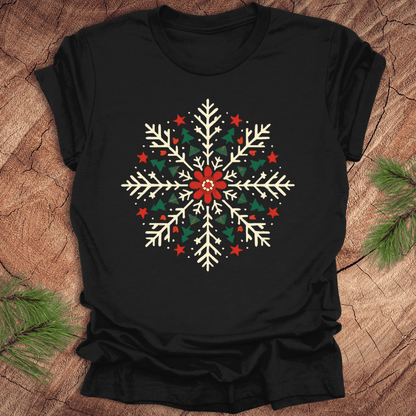 Black t-shirt with a colorful snowflake design on a wooden surface with pine branches.