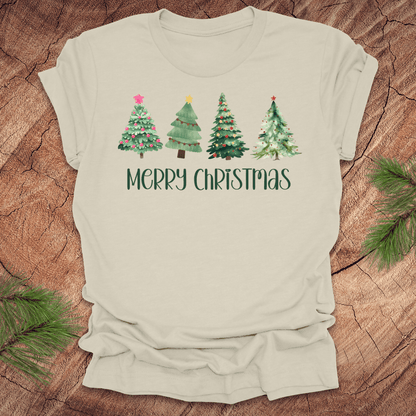 Beige tshirt with the text 'Merry Christmas' and christmas trees on a wood background.