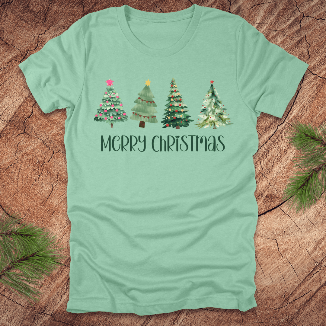 Mint green tshirt with the text 'Merry Christmas' and christmas trees on a wood background.