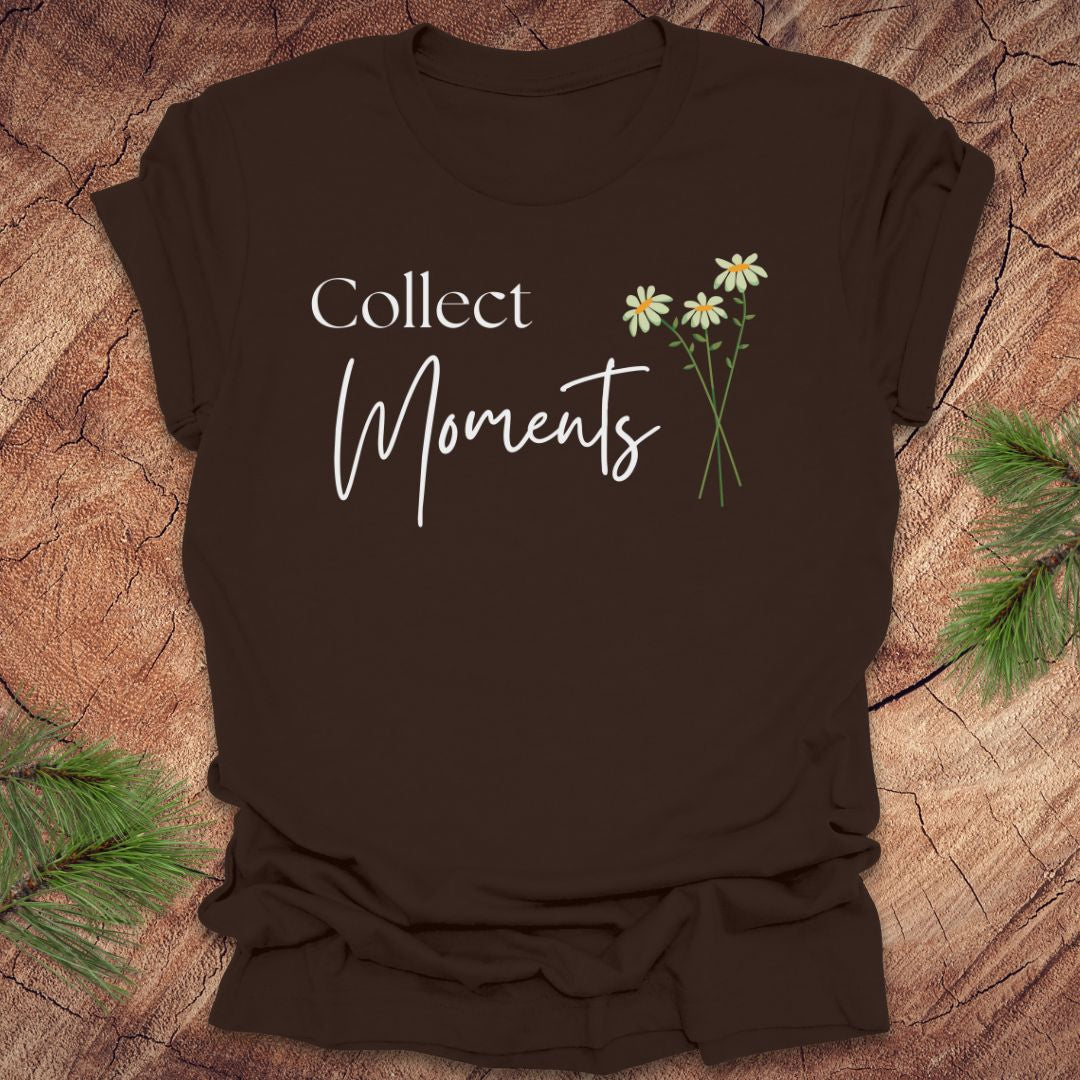 Brown t-shirt with 'Collect Moments' text and daisy design on a wooden surface.