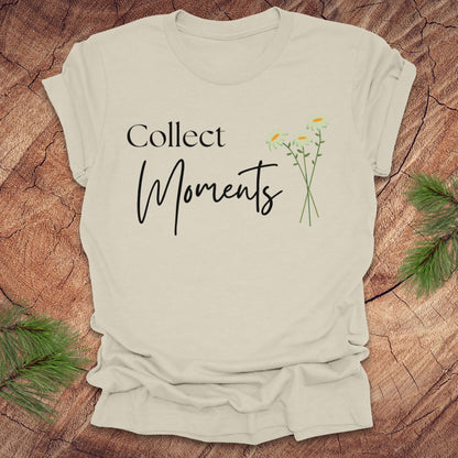 Beige t-shirt with 'Collect Moments' text and floral design on a wooden surface