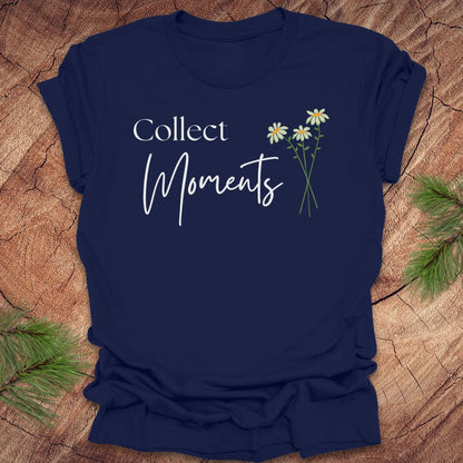 Navy blue t-shirt with 'Collect Moments' text and floral design on a wooden surface.