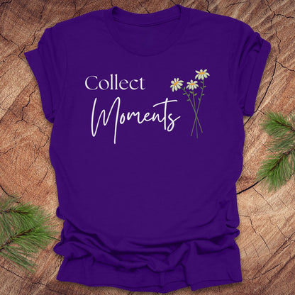 Purple t-shirt with 'Collect Moments' text and floral design on a wooden surface.