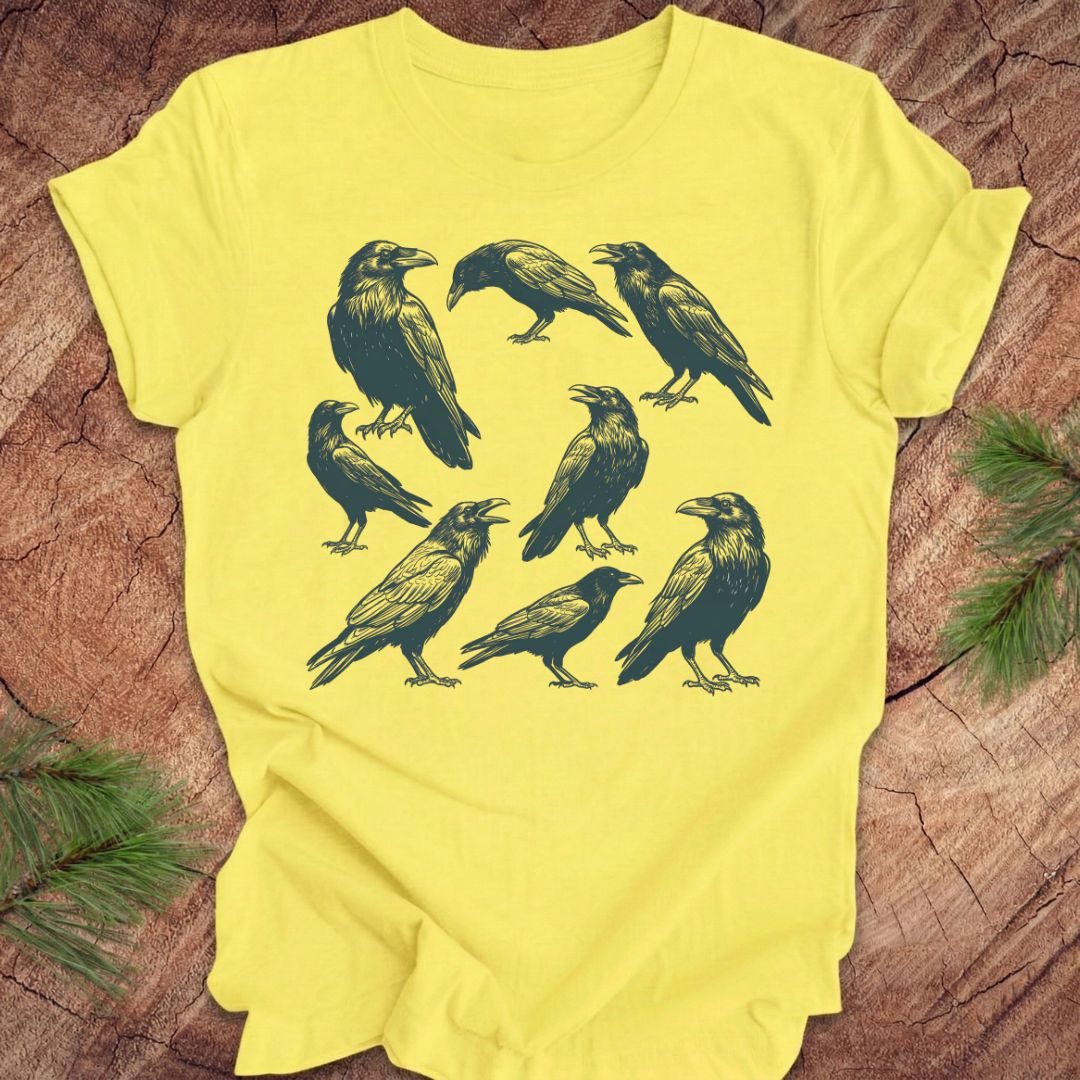Yellow t-shirt with black crow and raven illustrations on a wooden surface