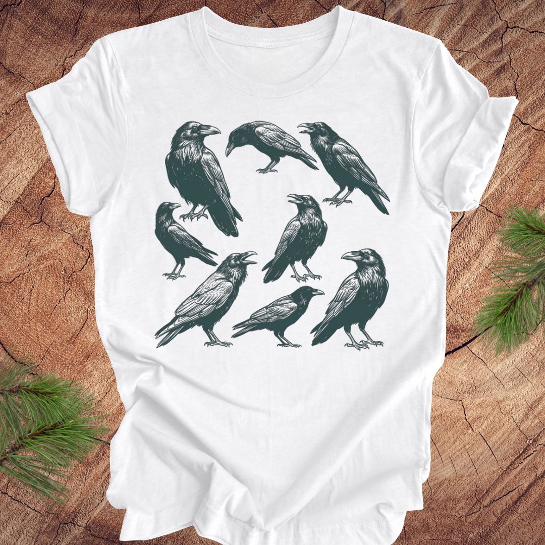 White t-shirt with black crow and raven illustrations on a wooden surface
