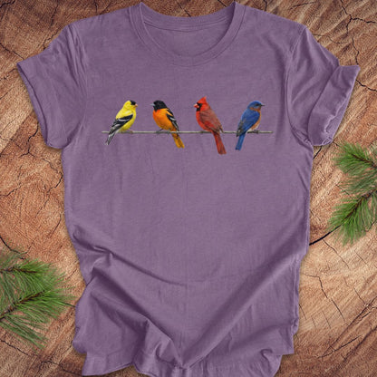 Purple t-shirt with colorful bird design on a wooden surface