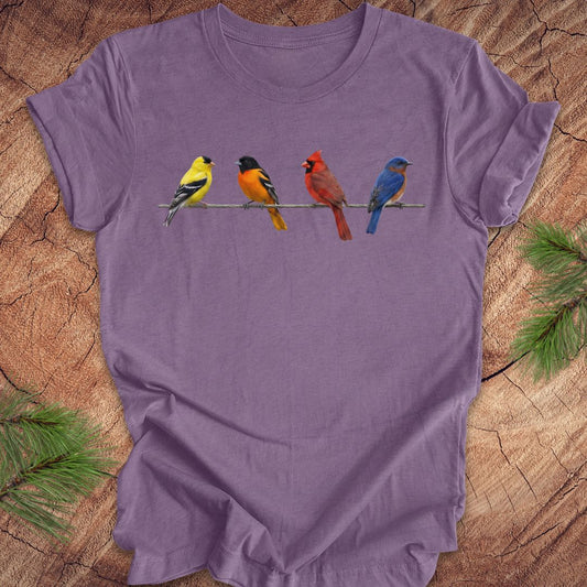 Purple t-shirt with colorful bird design on a wooden surface