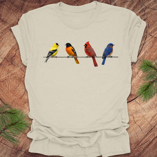 Beige t-shirt with colorful bird design on a wooden surface