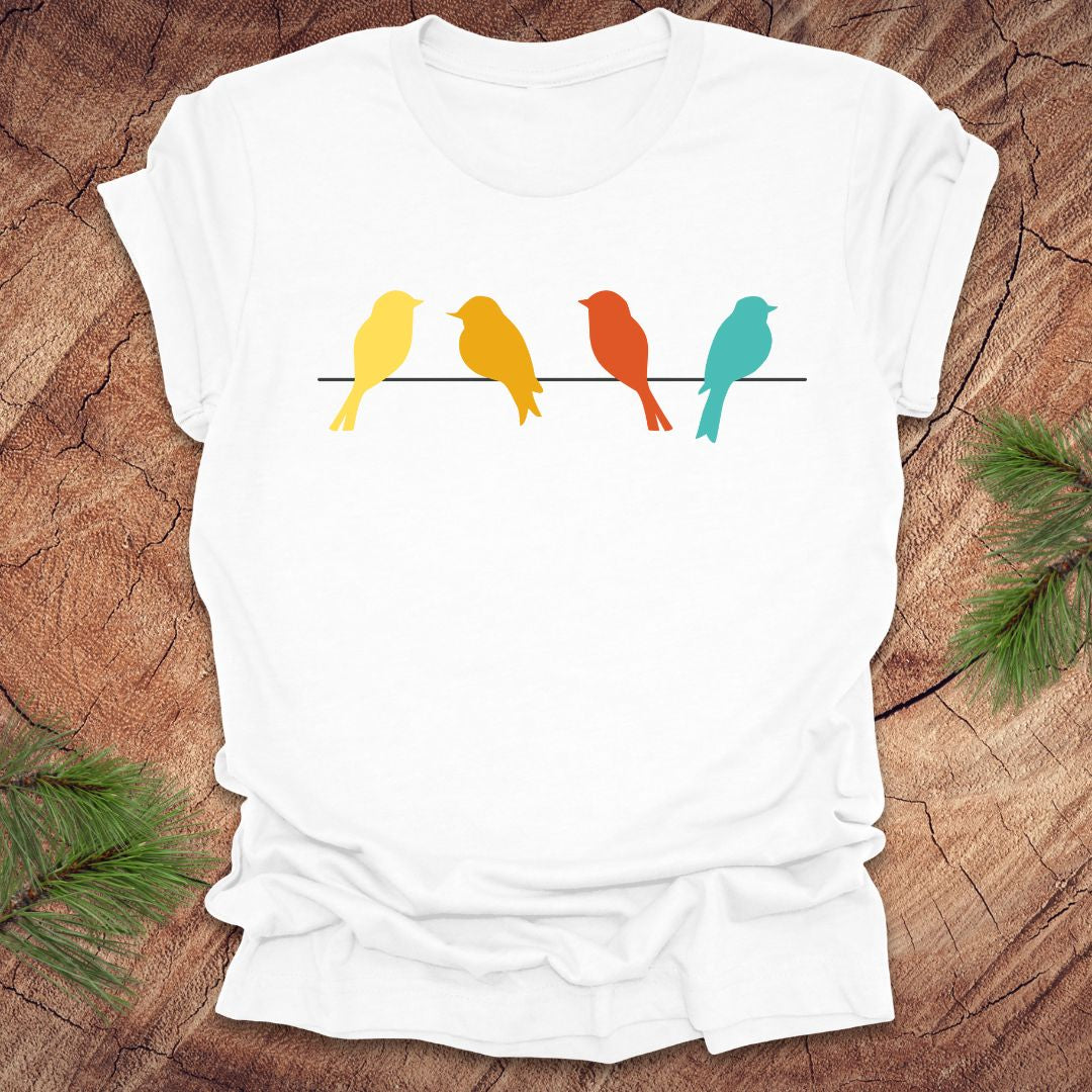 White t-shirt with colorful birds on a wire design on a wooden surface