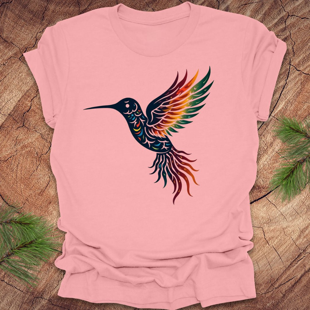 Pink t-shirt with a colorful hummingbird design on a wooden surface.