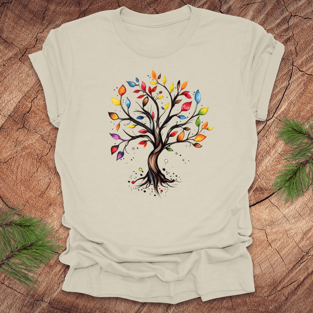 Beige tshirt with a colorful tree design on a wood background with pine leaves.