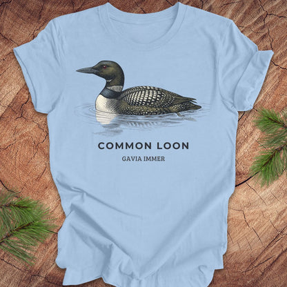 Blue t-shirt with a common loon on a wood background.