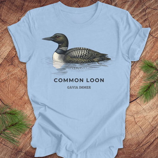 Blue t-shirt with a common loon on a wood background.