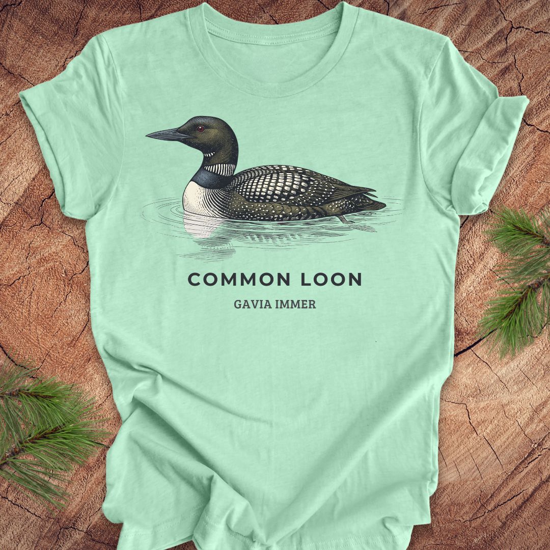Mint green t-shirt with a common loon on a wood background.