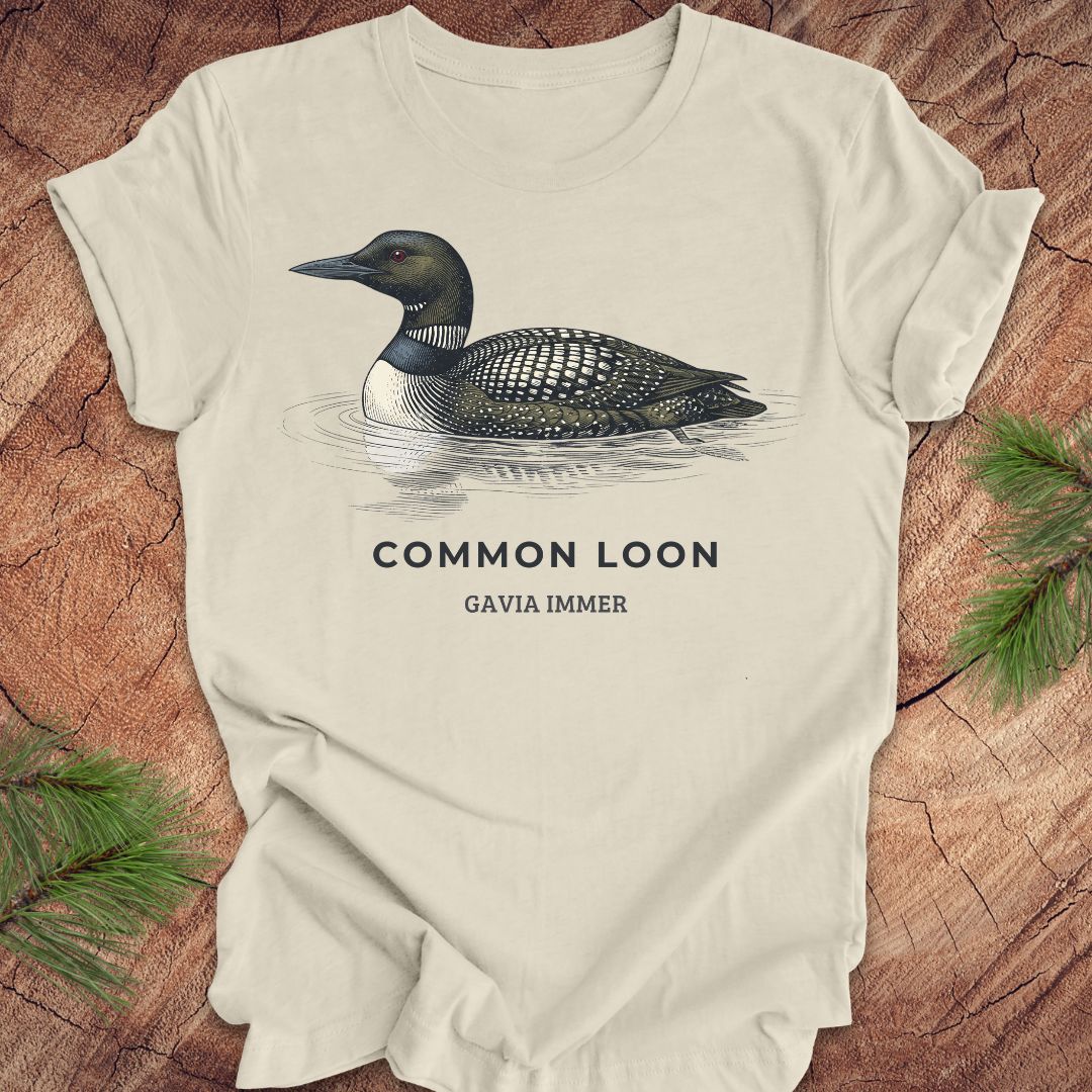 Beige t-shirt with a common loon on a wood background.