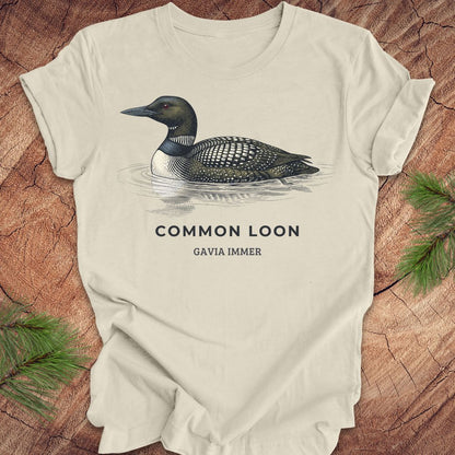 Beige t-shirt with a common loon on a wood background.