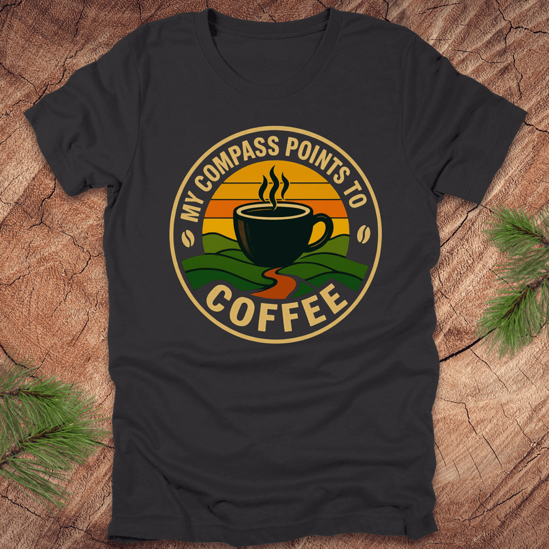 Dark grey t-shirt with a coffee-themed graphic and text, 'my compass points to coffee' on a wooden surface