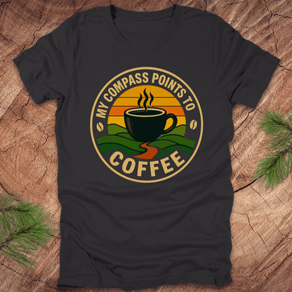 Dark grey t-shirt with a coffee-themed graphic and text, 'my compass points to coffee' on a wooden surface