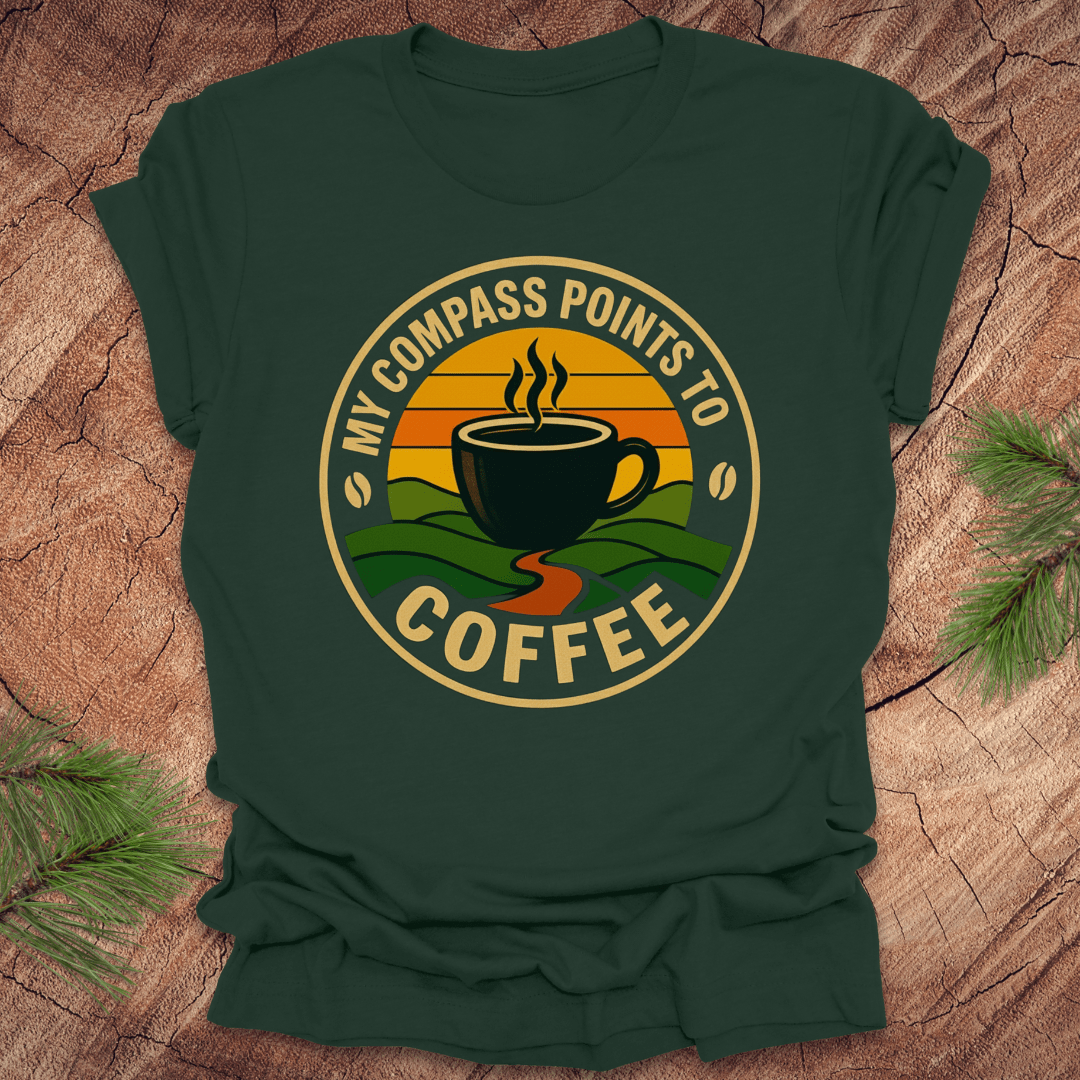 Green t-shirt with a coffee-themed graphic and text, 'my compass points to coffee' on a wooden surface