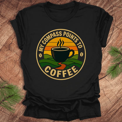 Black t-shirt with a coffee-themed graphic and text, 'my compass points to coffee' on a wooden surface
