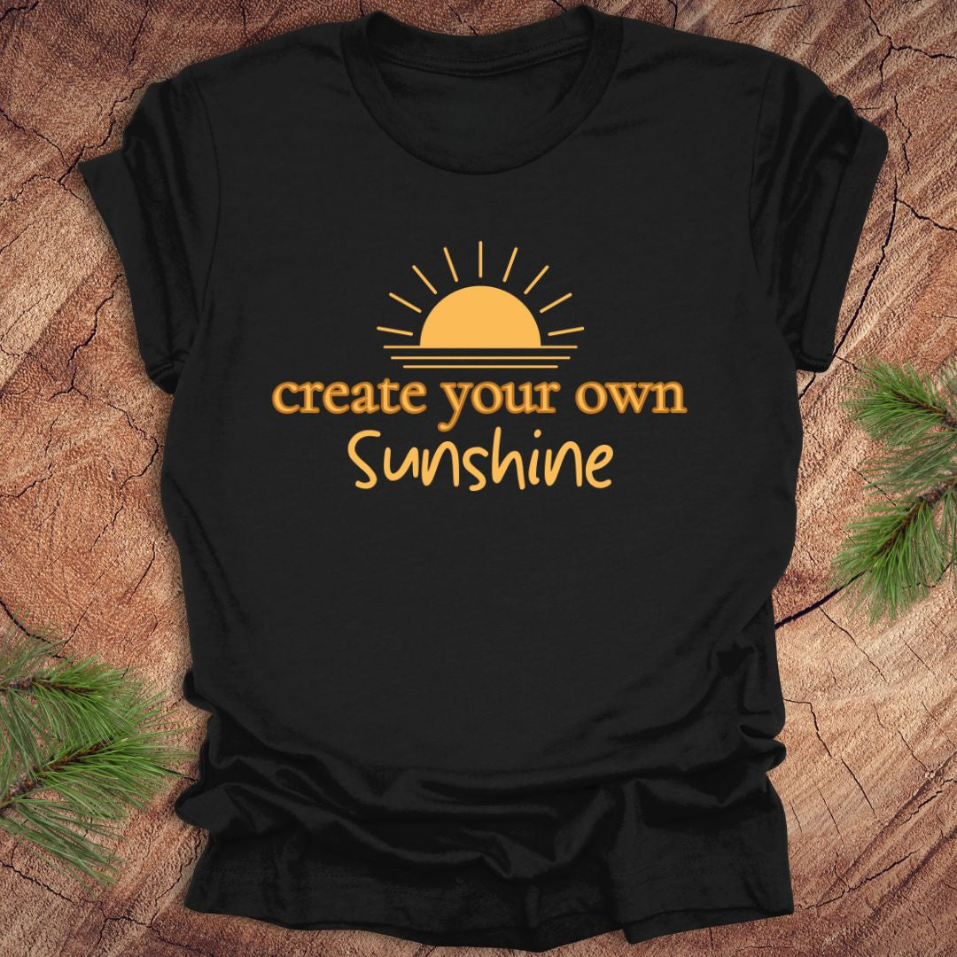Black t-shirt with 'create your own Sunshine' text and sun graphic on a wooden surface.