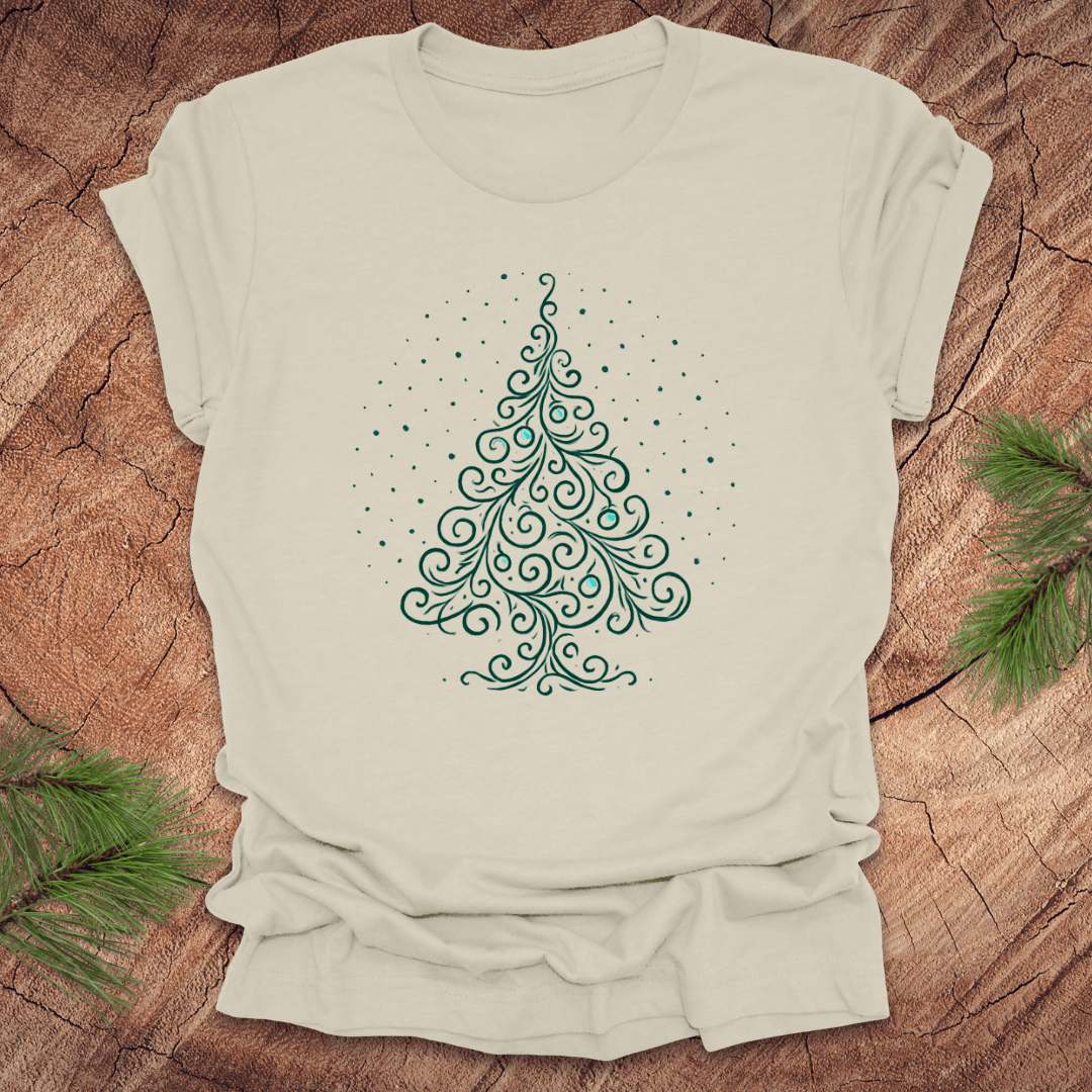 Beige t-shirt with a green Christmas tree design on a wooden surface with pine branches.