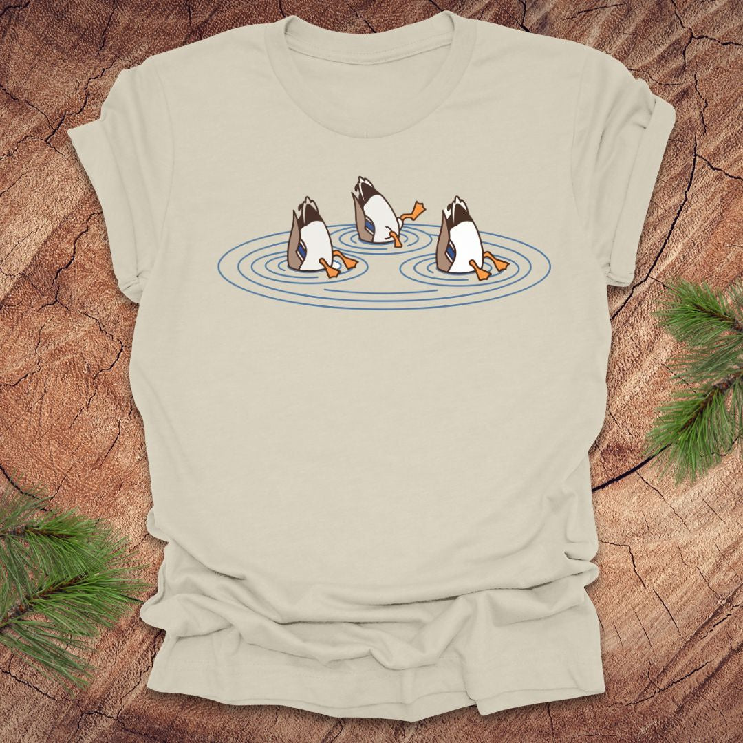 Beige t-shirt with cartoon ducks dabbling on a pond design on a wooden surface