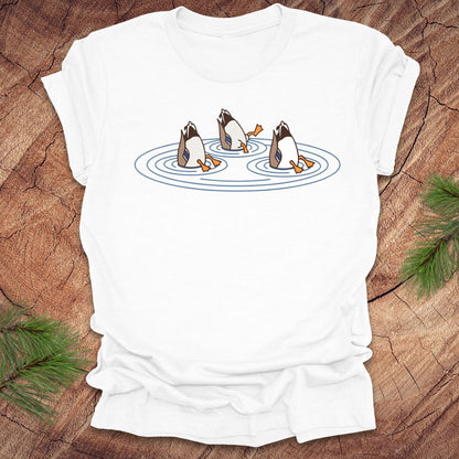 White t-shirt with cartoon ducks dabbling on a pond design on a wooden surface