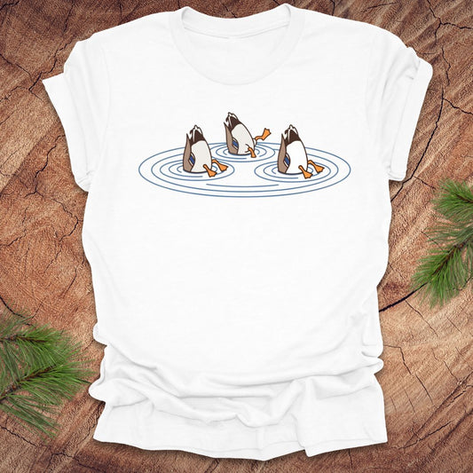White t-shirt with cartoon ducks dabbling on a pond design on a wooden surface