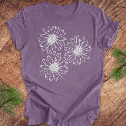 Purple t-shirt with daisy designs on a wooden surface