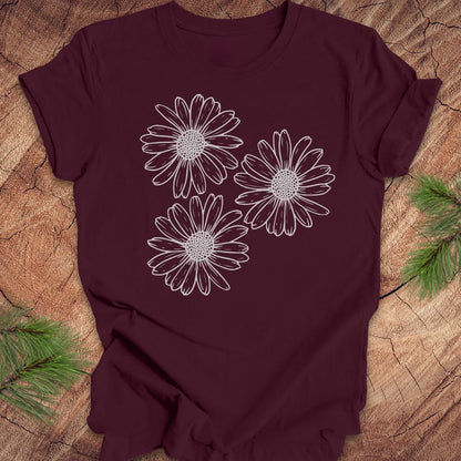 Maroon t-shirt with daisy designs on a wooden surface