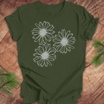 Green t-shirt with daisy designs on a wooden surface