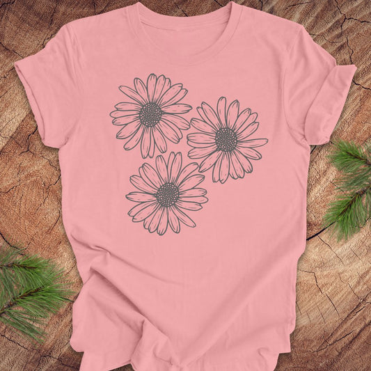 Pink t-shirt with daisy designs on a wooden surface