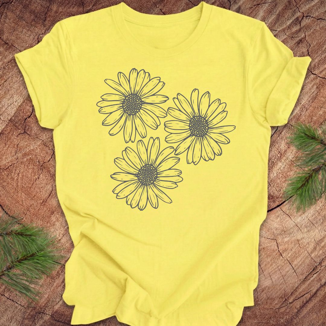 Yellow t-shirt with daisy designs on a wooden surface