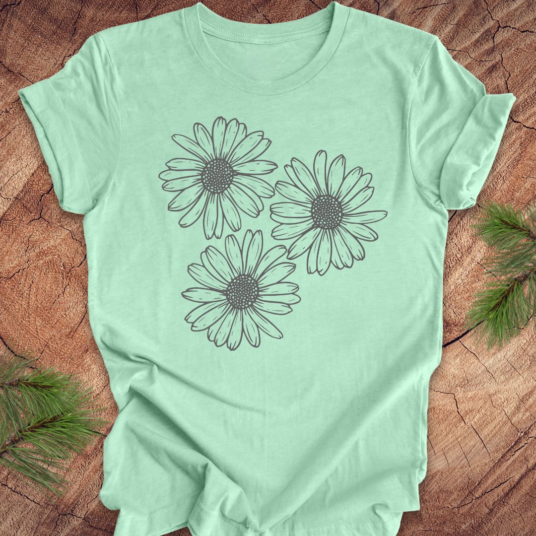 Mint green t-shirt with daisy designs on a wooden surface