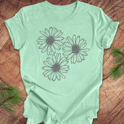 Mint green t-shirt with daisy designs on a wooden surface
