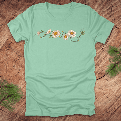 Mint green t-shirt with daisy design on a wooden surface