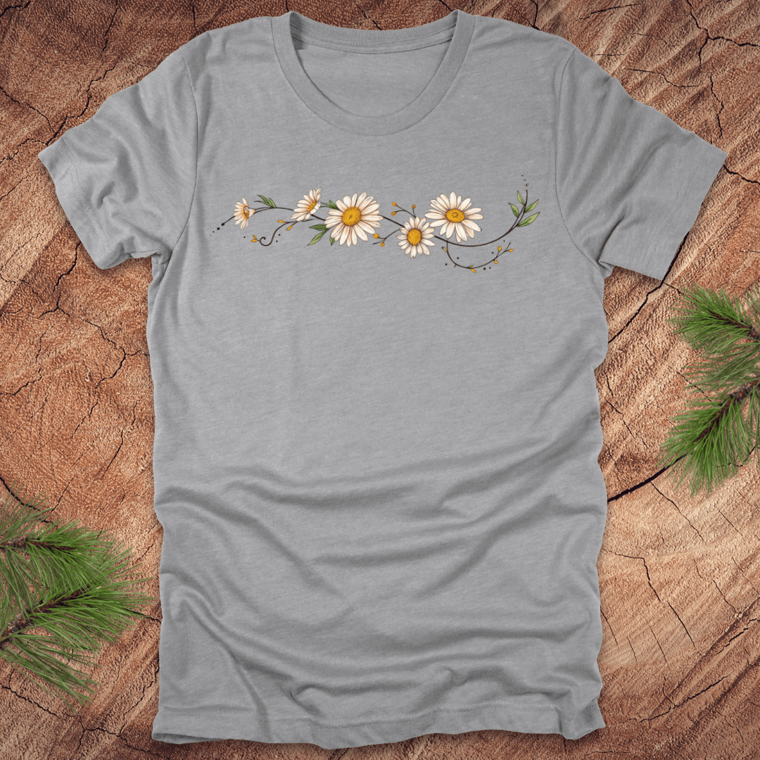 Gray t-shirt with daisy design on a wooden surface