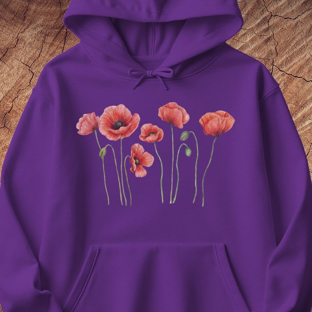 A purple pullover hoodie featuring a graphic print of pink poppy flowers with green stems across the chest, displayed flat against a textured brown wood background.