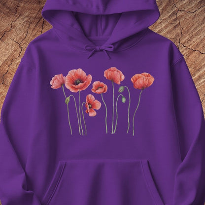 A purple pullover hoodie featuring a graphic print of pink poppy flowers with green stems across the chest, displayed flat against a textured brown wood background.