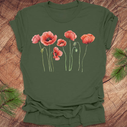 Green t-shirt with red poppy flower design on a wooden surface