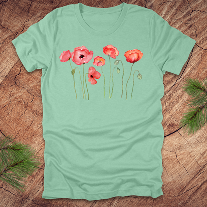 Mint green t-shirt with red poppy design on a wooden surface