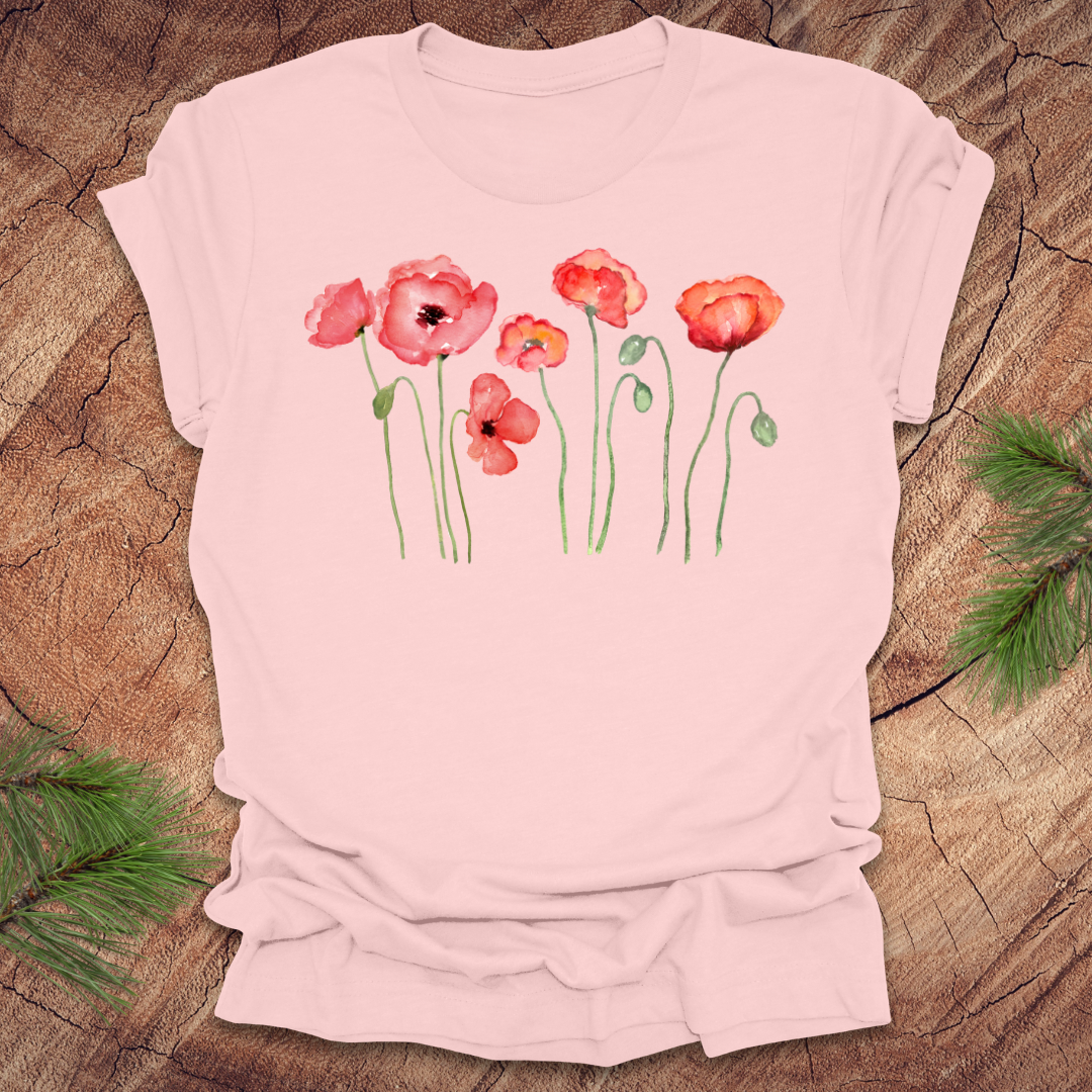 Pink t-shirt with red poppy design on a wooden surface