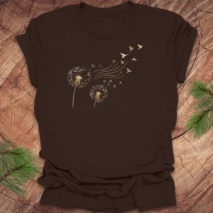 Brown t-shirt with dandelion and bird graphic on a wooden surface